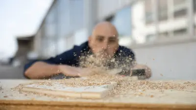 Christoph Bühlen, associate at Bosch Power Tools, sweeping sawdust and shavings off a piece of wood.