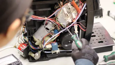 Close-up of a woman repairing a defective coffee machine.
