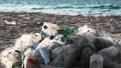 The image depicts a beach where plastic waste has washed ashore.